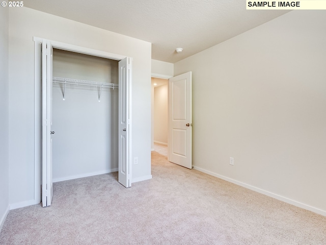 unfurnished bedroom with carpet flooring, baseboards, and a closet