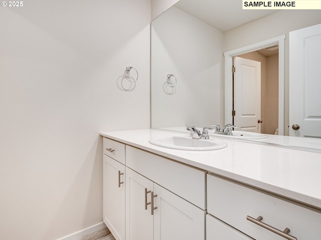 bathroom featuring vanity, toilet, and baseboards