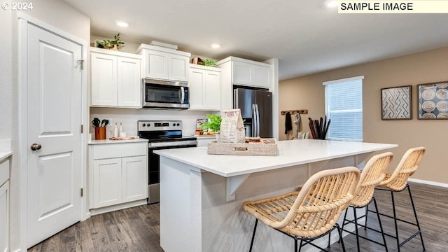 kitchen featuring a kitchen island, appliances with stainless steel finishes, a kitchen breakfast bar, white cabinets, and dark wood-style flooring