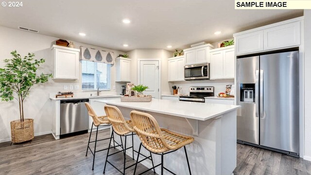 kitchen with white cabinetry, dark wood-type flooring, stainless steel appliances, and a kitchen island