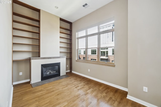 unfurnished living room with baseboards, plenty of natural light, and a fireplace with flush hearth
