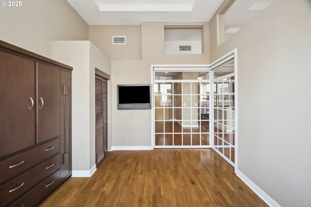 unfurnished bedroom with wood finished floors, baseboards, and a towering ceiling