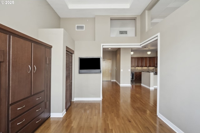 corridor with wood finished floors, a towering ceiling, and baseboards