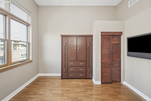 unfurnished bedroom with light wood-type flooring, a closet, and baseboards