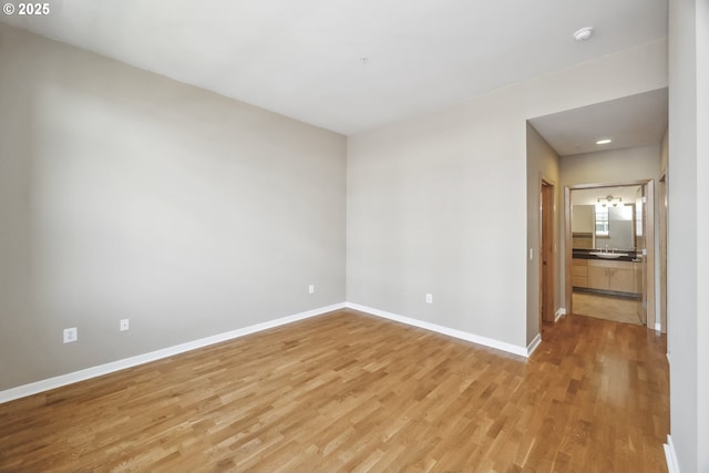 empty room featuring light wood-type flooring, baseboards, a smoke detector, and recessed lighting
