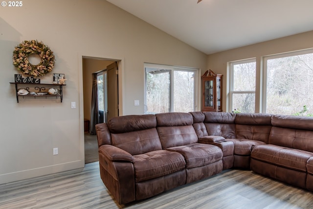 living room featuring baseboards, high vaulted ceiling, and light wood finished floors