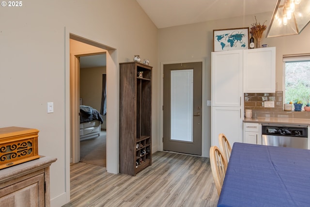 kitchen with tasteful backsplash, dishwasher, light countertops, light wood-type flooring, and white cabinets