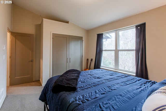 bedroom featuring a closet, lofted ceiling, and light carpet