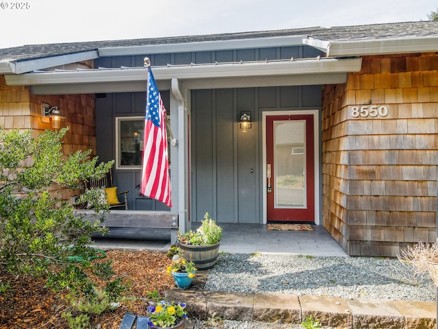 property entrance featuring board and batten siding and roof with shingles