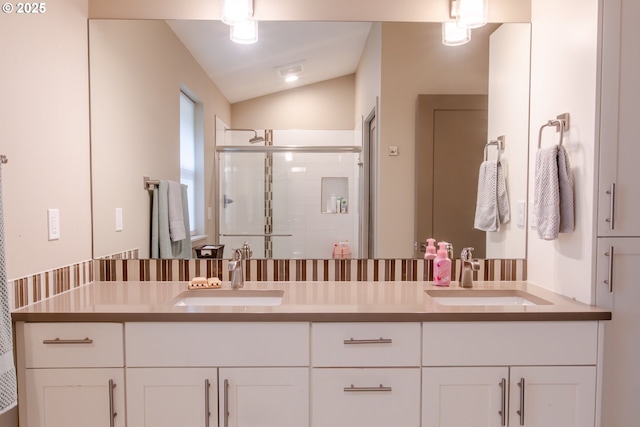 full bathroom featuring a shower stall, vaulted ceiling, double vanity, and a sink