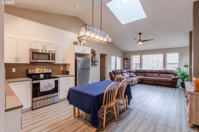 kitchen featuring open floor plan, appliances with stainless steel finishes, white cabinetry, and light countertops