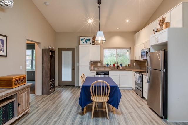 kitchen featuring backsplash, white cabinetry, stainless steel appliances, and light wood-type flooring