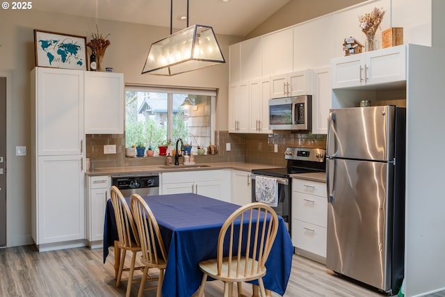 kitchen with a sink, decorative backsplash, white cabinets, and stainless steel appliances