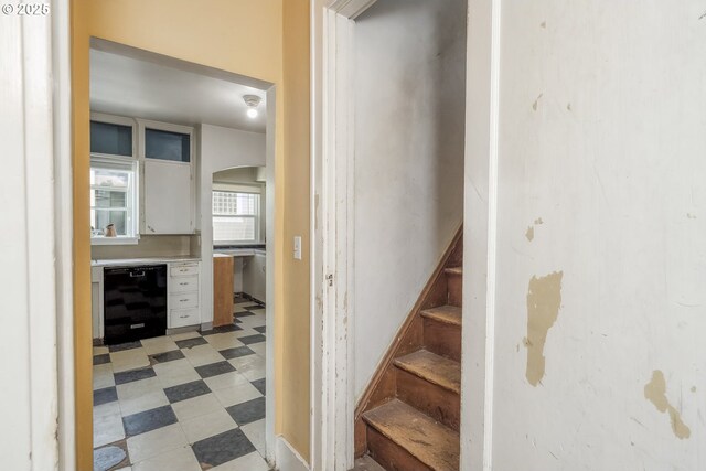 staircase featuring wine cooler, arched walkways, and tile patterned floors