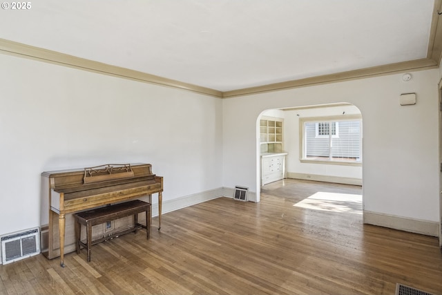 spare room with arched walkways, wood finished floors, and baseboards