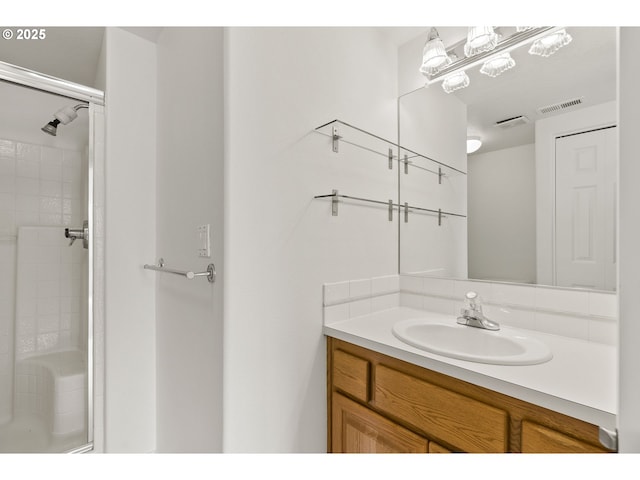 bathroom featuring vanity, a shower, and visible vents