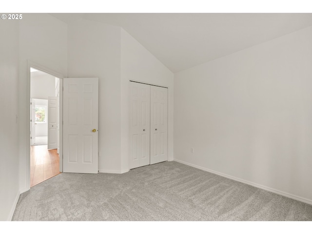unfurnished bedroom with carpet floors, baseboards, a closet, and high vaulted ceiling