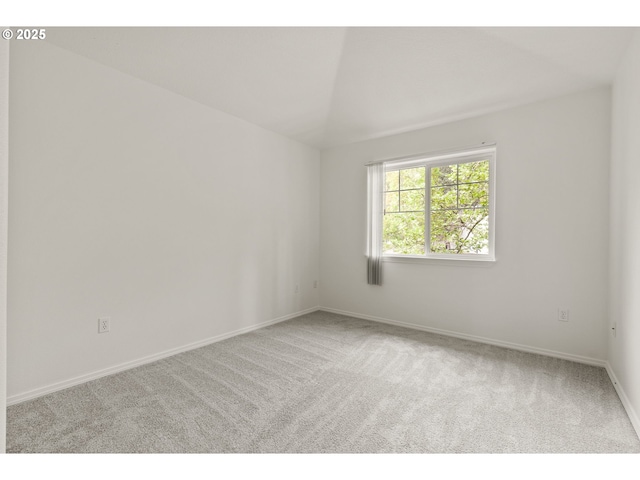 spare room featuring baseboards, carpet flooring, and vaulted ceiling