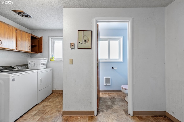laundry area featuring washing machine and dryer, heating unit, baseboards, a textured ceiling, and cabinet space