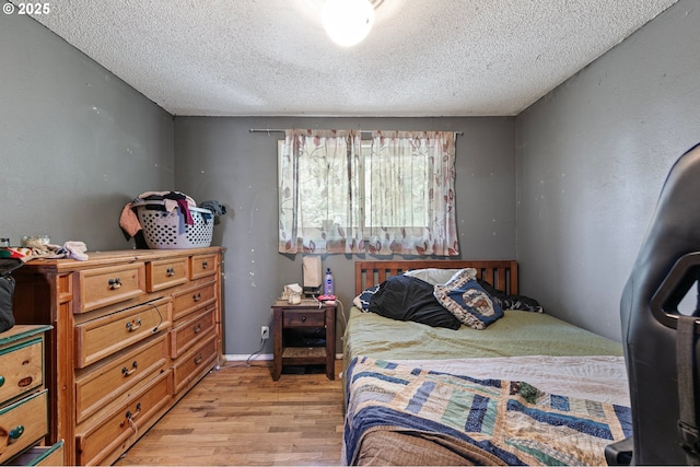 bedroom with a textured ceiling and light wood-style floors