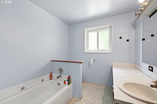 full bath with a garden tub, vanity, marble finish flooring, and baseboards