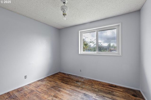 unfurnished room featuring wood finished floors, baseboards, and a textured ceiling