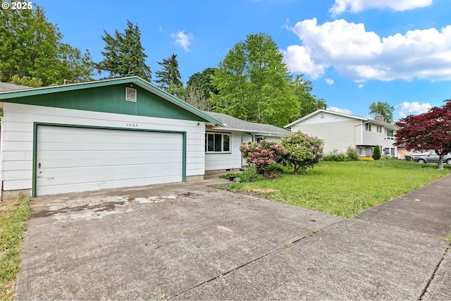 single story home featuring a garage, a front lawn, and concrete driveway
