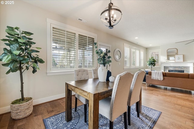 dining space featuring light wood-type flooring, a fireplace, and a chandelier