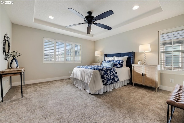 carpeted bedroom with a tray ceiling and ceiling fan