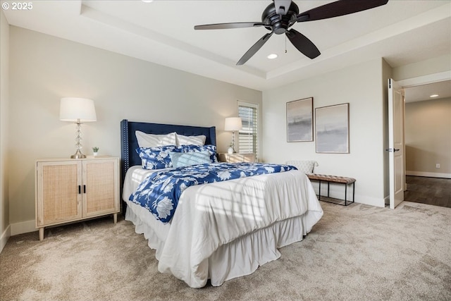 carpeted bedroom with a raised ceiling and ceiling fan