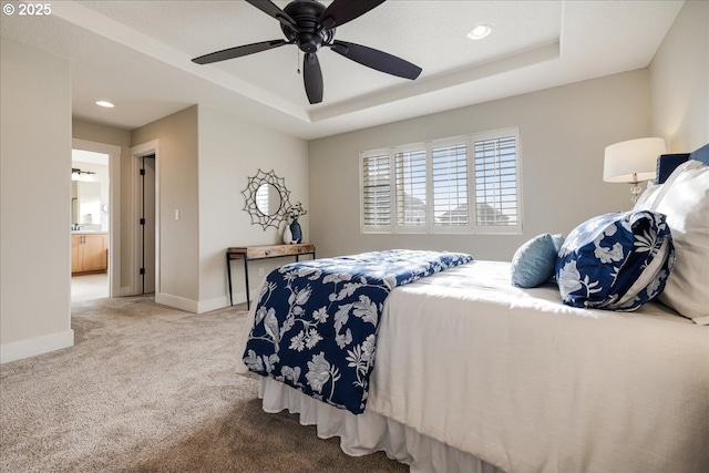 bedroom with a tray ceiling, connected bathroom, ceiling fan, and carpet flooring