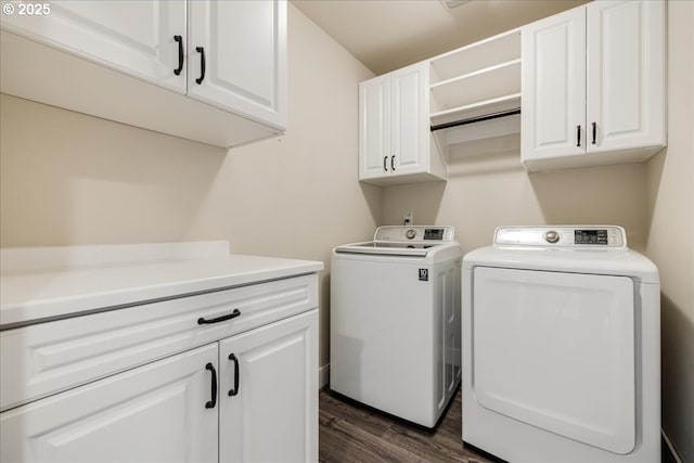 clothes washing area with cabinets, washing machine and dryer, and dark hardwood / wood-style floors