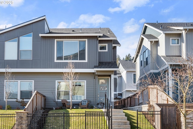 view of front facade featuring a fenced front yard, a front yard, and roof with shingles