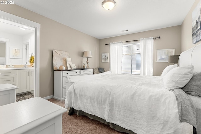 carpeted bedroom featuring baseboards, visible vents, ensuite bathroom, and a sink