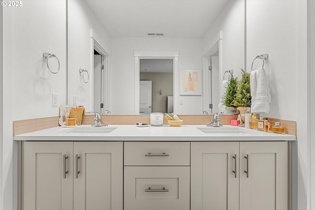 full bath with a sink, visible vents, and double vanity