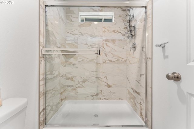 bathroom featuring a marble finish shower and toilet