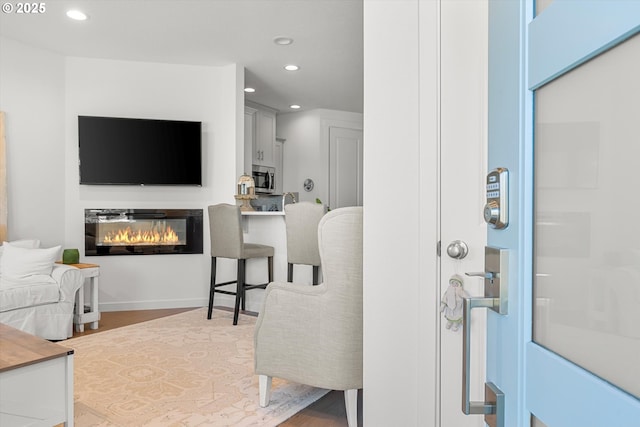 foyer with a glass covered fireplace, wood finished floors, and recessed lighting