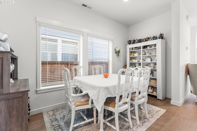 dining room with light wood finished floors, visible vents, and baseboards