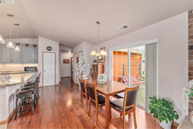 13130 Lookingglass Rd, Winston, OR 97496 - dining area with vaulted ceiling, dark wood-style floors, baseboards, visible vents, and an inviting chandelier