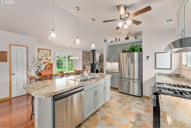 13130 Lookingglass Rd, Winston, OR 97496 - kitchen featuring visible vents, appliances with stainless steel finishes, under cabinet range hood, a sink, and a wood stove