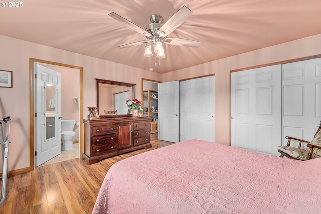 13130 Lookingglass Rd, Winston, OR 97496 - bedroom with two closets, baseboards, a ceiling fan, ensuite bathroom, and wood finished floors