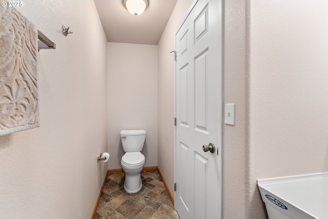 13130 Lookingglass Rd, Winston, OR 97496 - bathroom featuring baseboards, toilet, and stone tile floors
