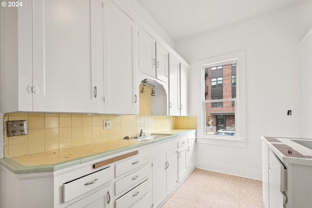 kitchen featuring sink, decorative backsplash, tile counters, and white cabinets