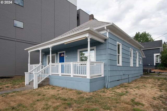 bungalow-style home with a front yard and covered porch