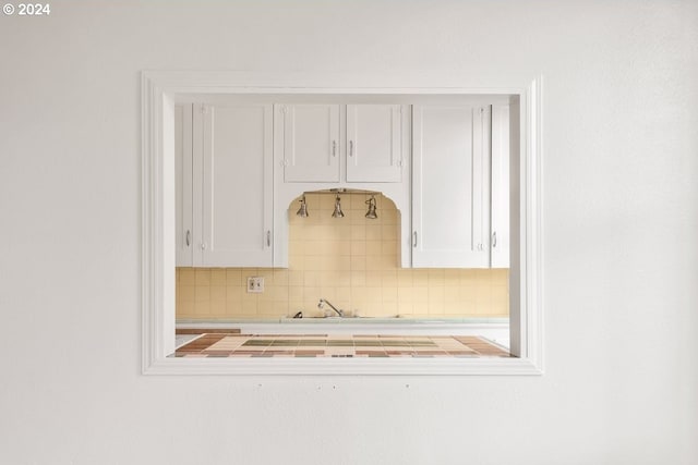 kitchen with tasteful backsplash, white cabinetry, and tile countertops