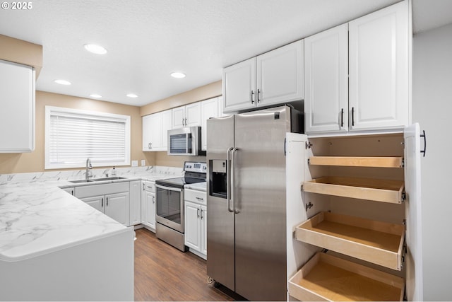 kitchen with light stone counters, sink, white cabinets, and appliances with stainless steel finishes