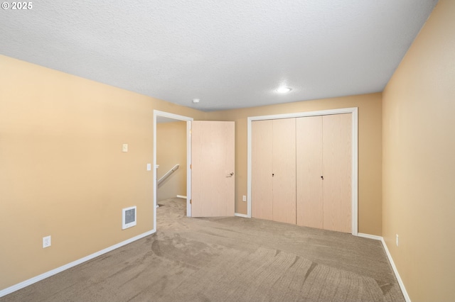 unfurnished bedroom with carpet floors, a textured ceiling, and a closet