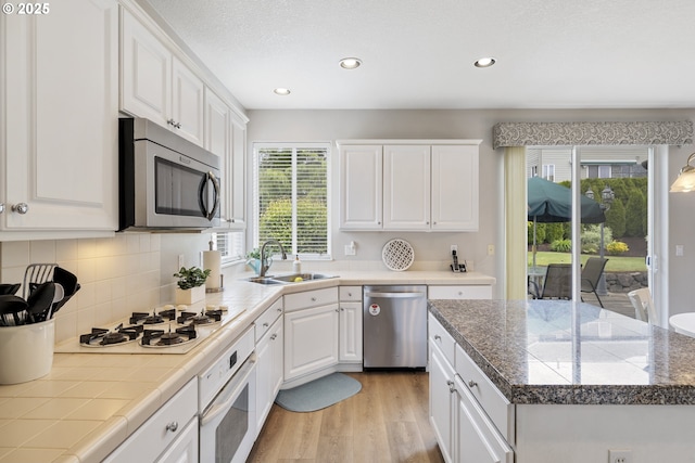 16205 SW Blackbird Dr, Beaverton, OR 97007 - kitchen with appliances with stainless steel finishes, a sink, white cabinets, recessed lighting, and light wood-style floors