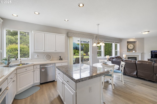 16205 SW Blackbird Dr, Beaverton, OR 97007 - kitchen with dishwasher, a sink, a kitchen island, a glass covered fireplace, and light wood-type flooring