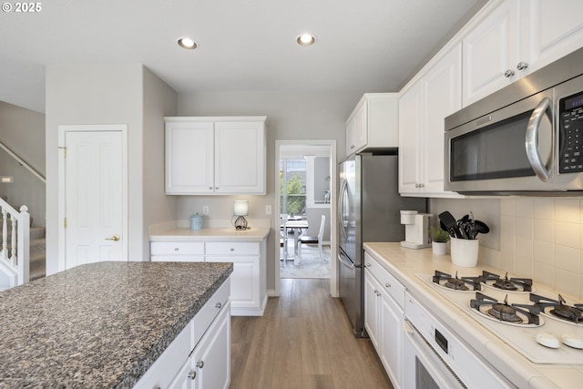 16205 SW Blackbird Dr, Beaverton, OR 97007 - kitchen with appliances with stainless steel finishes, white cabinetry, light wood-style floors, recessed lighting, and decorative backsplash
